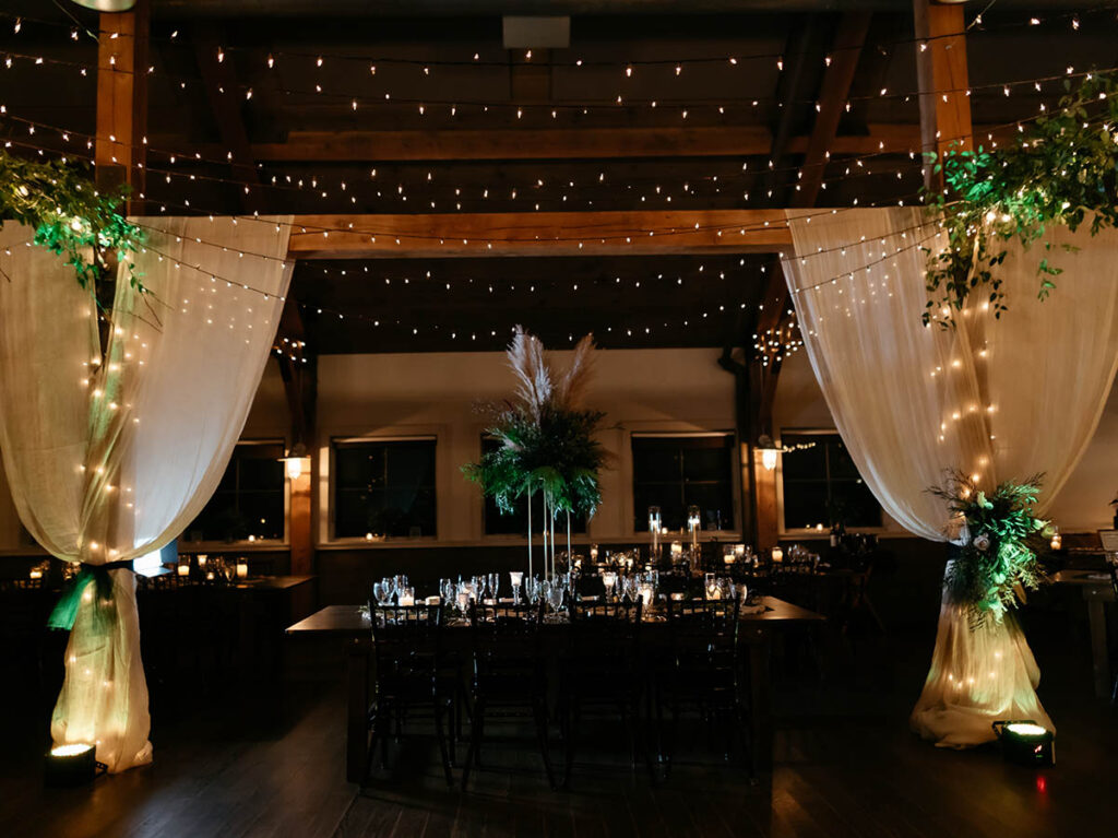 interior of reception barn room with candles, flowers and drapery